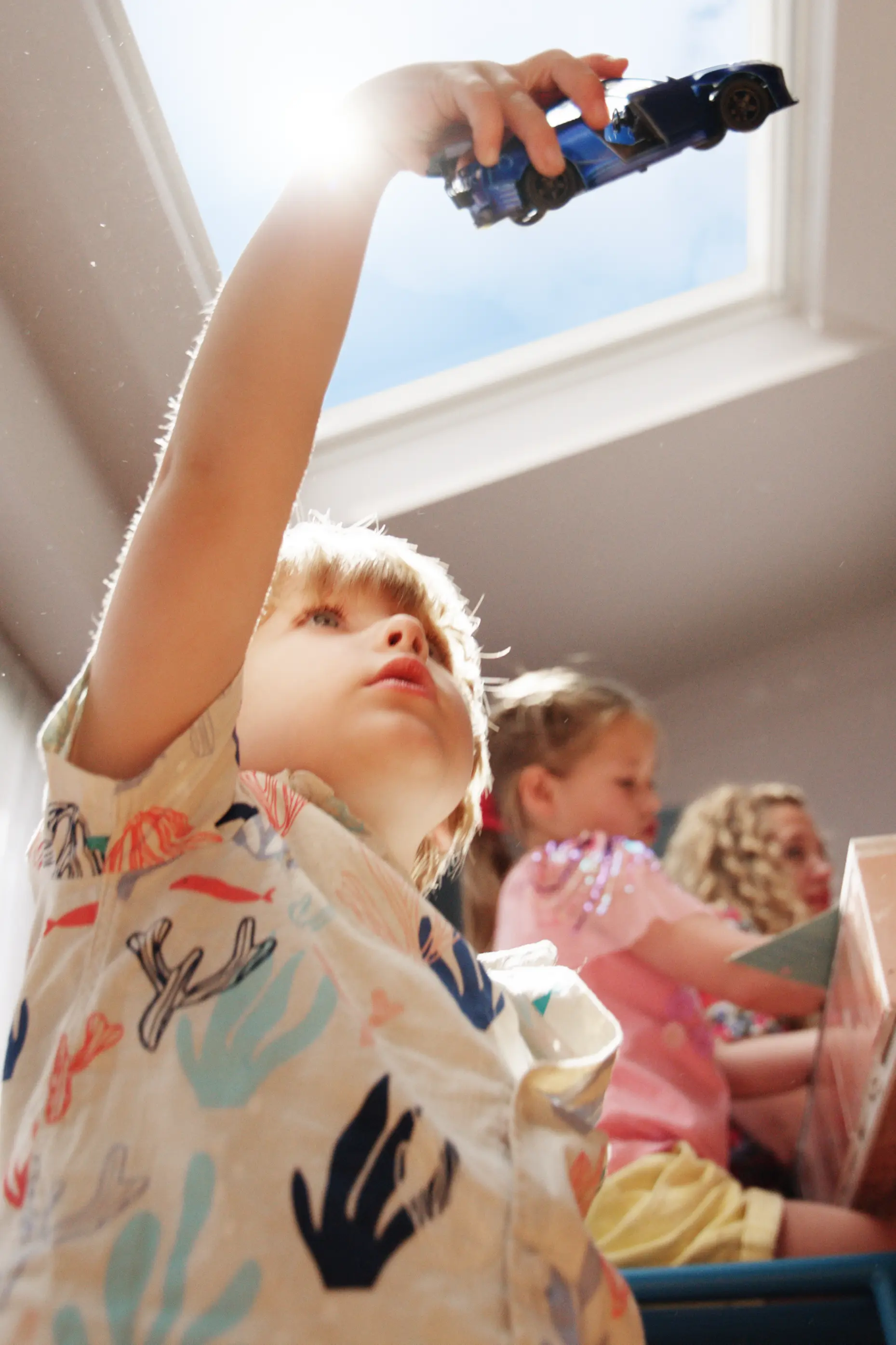 Dziecko bawi się zabawkową ciężarówką, w tle płaskie okno dachowe VELUX.