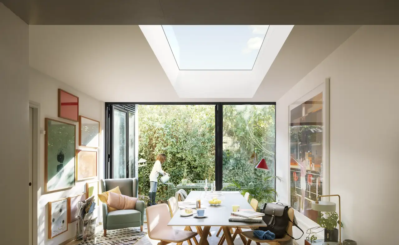 Espace repas avec fenêtre de toit plat VELUX et suspensions colorées apportant une lumière douce et décorative