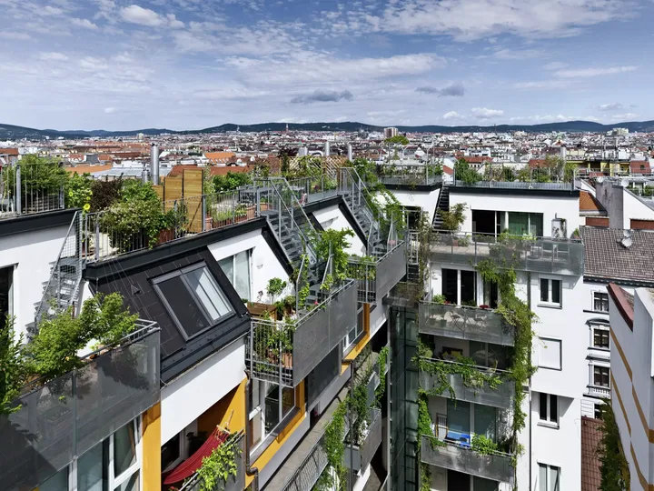 Modernes Apartmentgebäude mit VELUX Dachflächenfenstern und grünen Terrassen vor der Kulisse der Stadt.