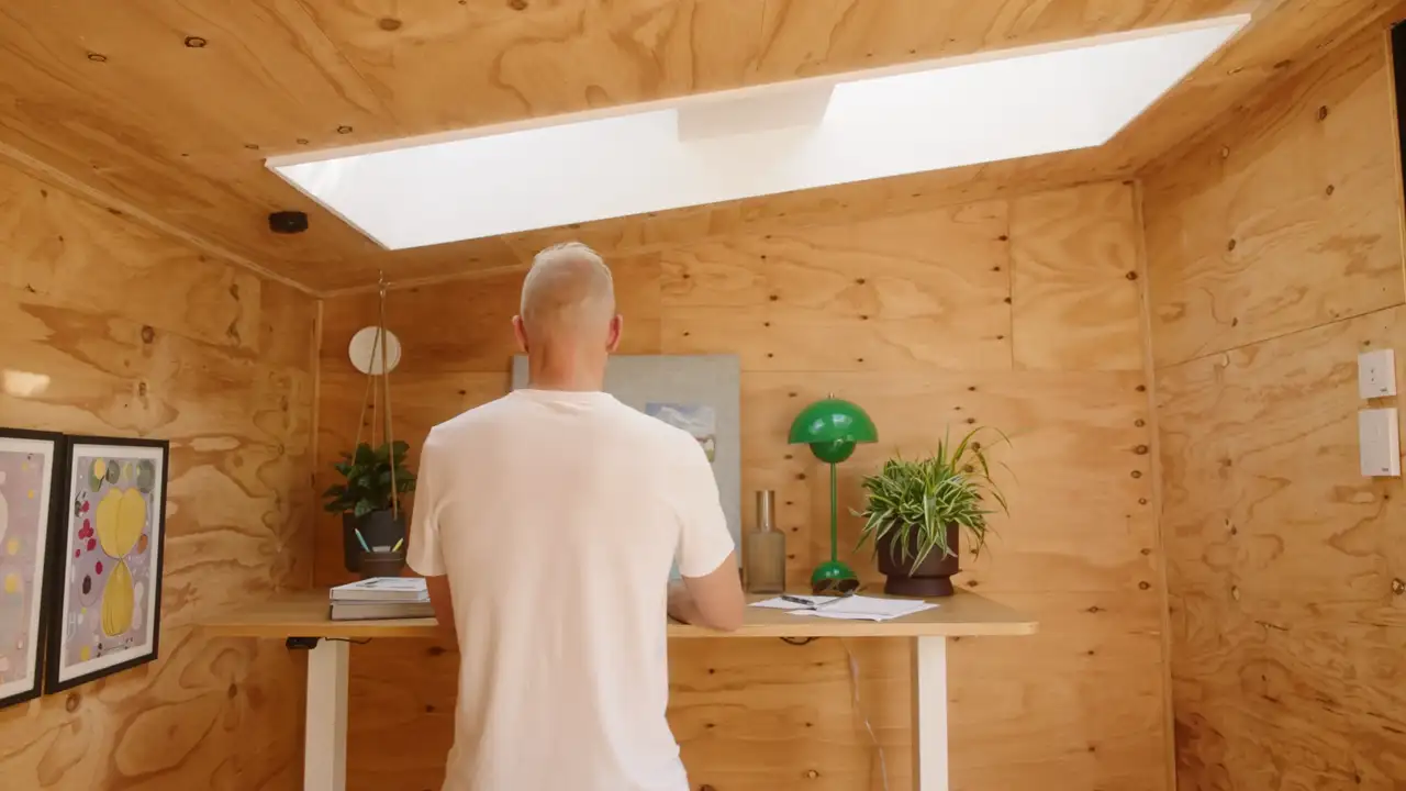 Mann steht im holzvertäfelten Arbeitszimmer unterm Dachfenster | VELUX Magazin