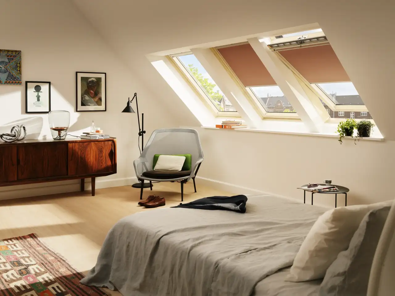 Attic bedroom with sloped ceiling and VELUX roof windows, natural light entering.