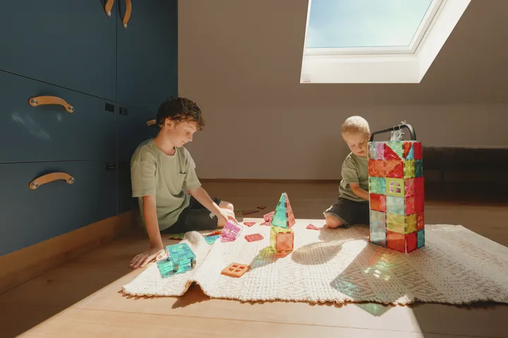 Děti si hrají na podlaze v dětském pokoji se střešním oknem VELUX | VELUX