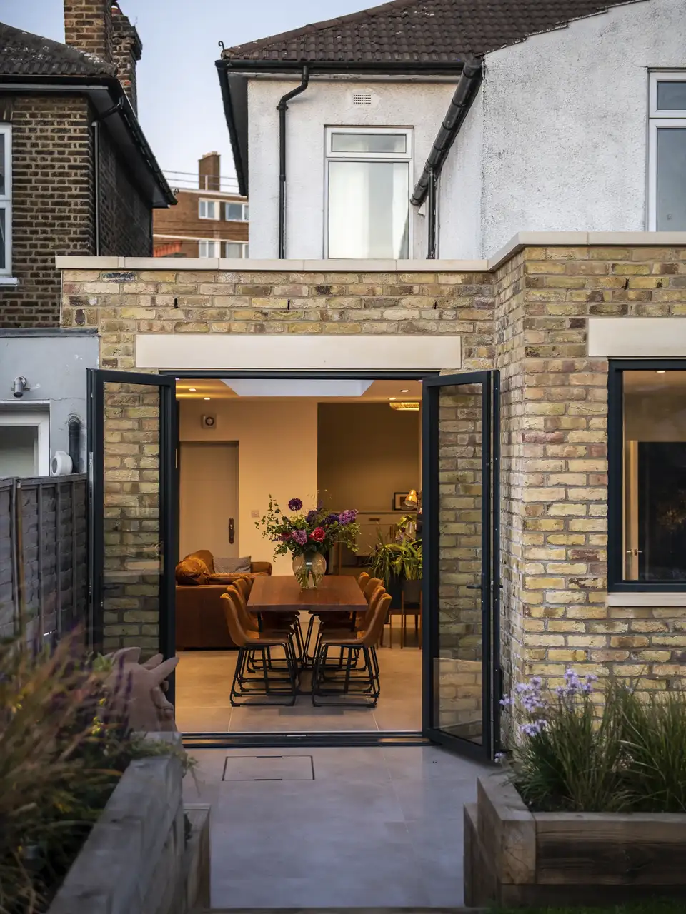 "Extension moderne avec portes vitrées révélant une salle à manger à l’intérieur."