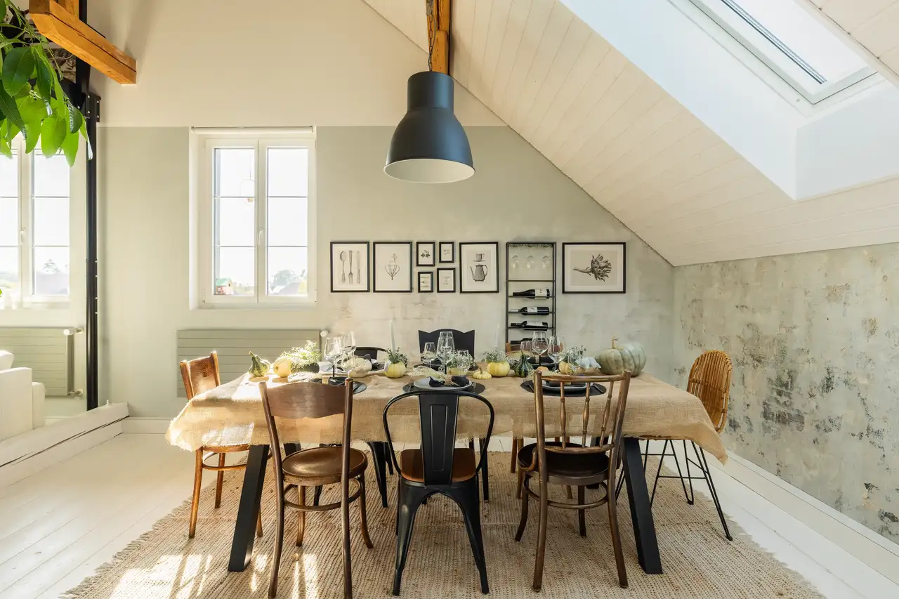 Çatı katında, sıcak renklerle dekore edilmiş ve VELUX çatı pencereleri bulunan bir yemek odası.