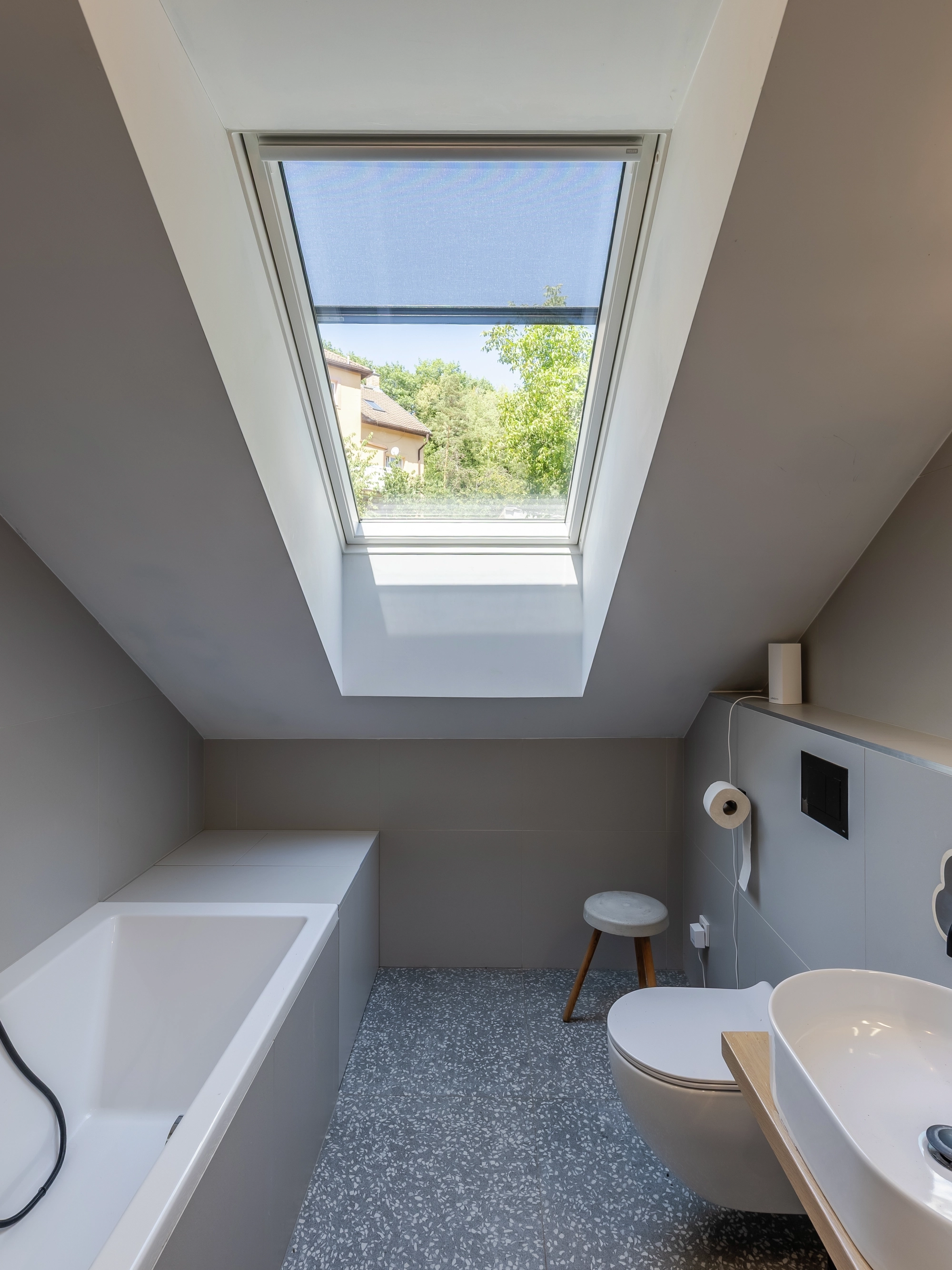Attic bathroom with sloped ceiling and VELUX roof window.