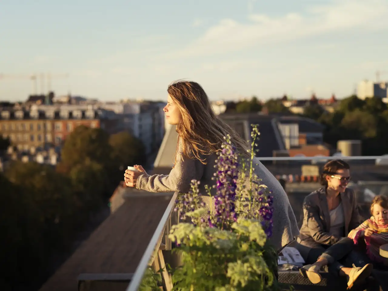 Una persona affacciata al parapetto di una terrazza costruita su un tetto piano