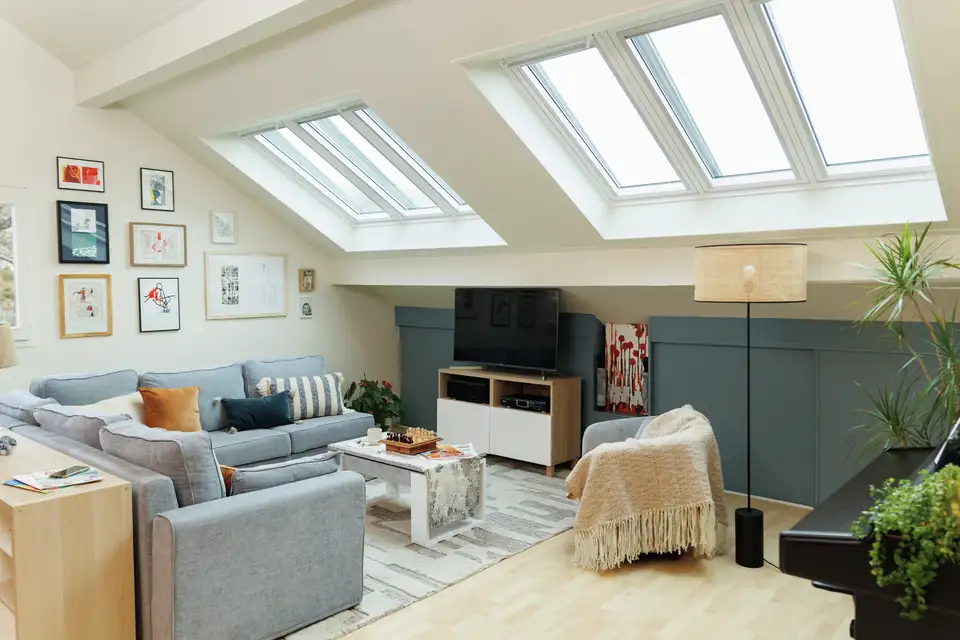 Salon lumineux aménagé sous les combles avec trois fenêtres de toit. 