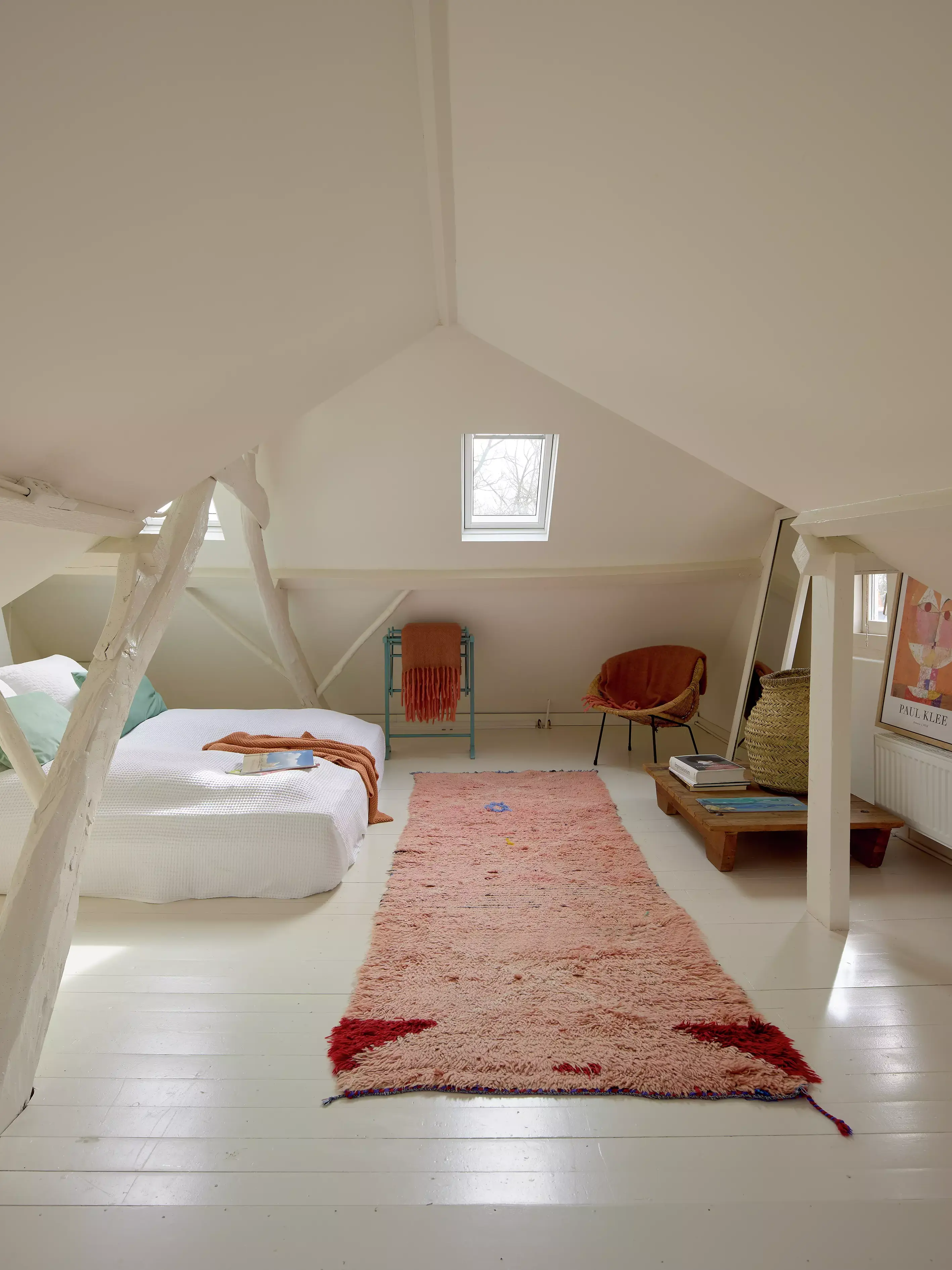 Chambre mansardée confortable avec lumière naturelle provenant d'une fenêtre de toit VELUX, tapis moelleux et coin lecture.