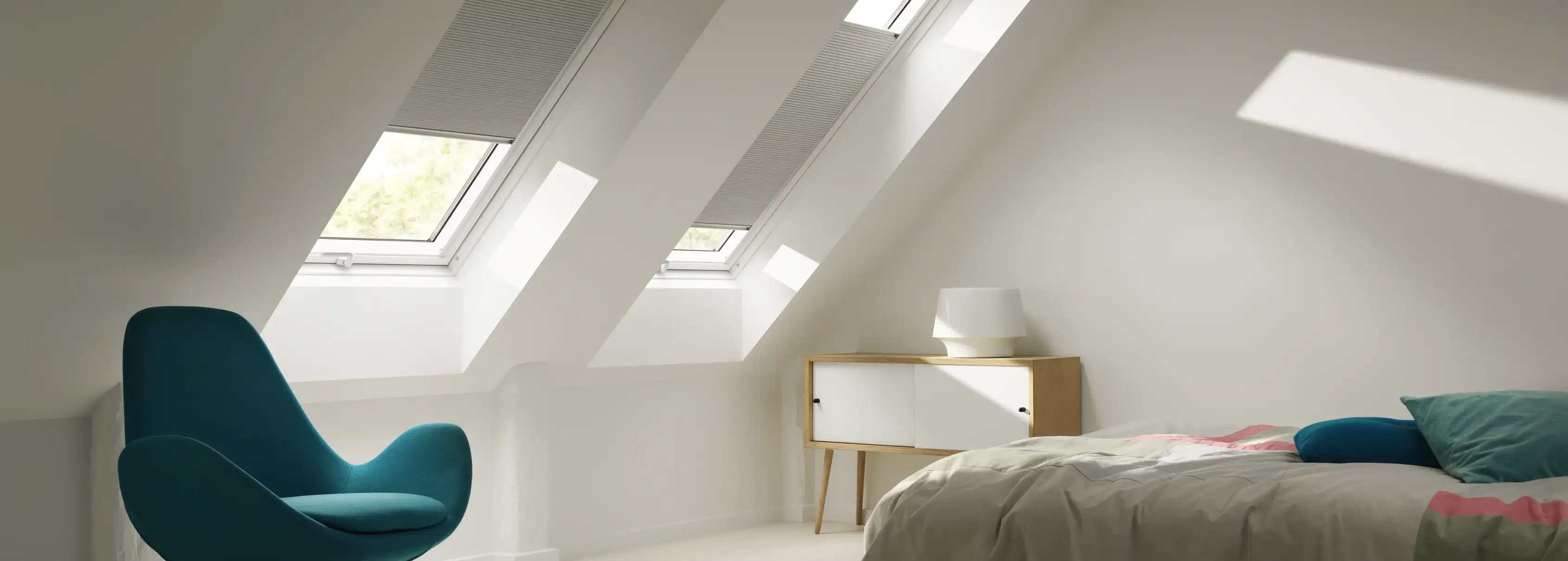 Attic bedroom with sloped ceiling and VELUX roof windows, modern furnishings.