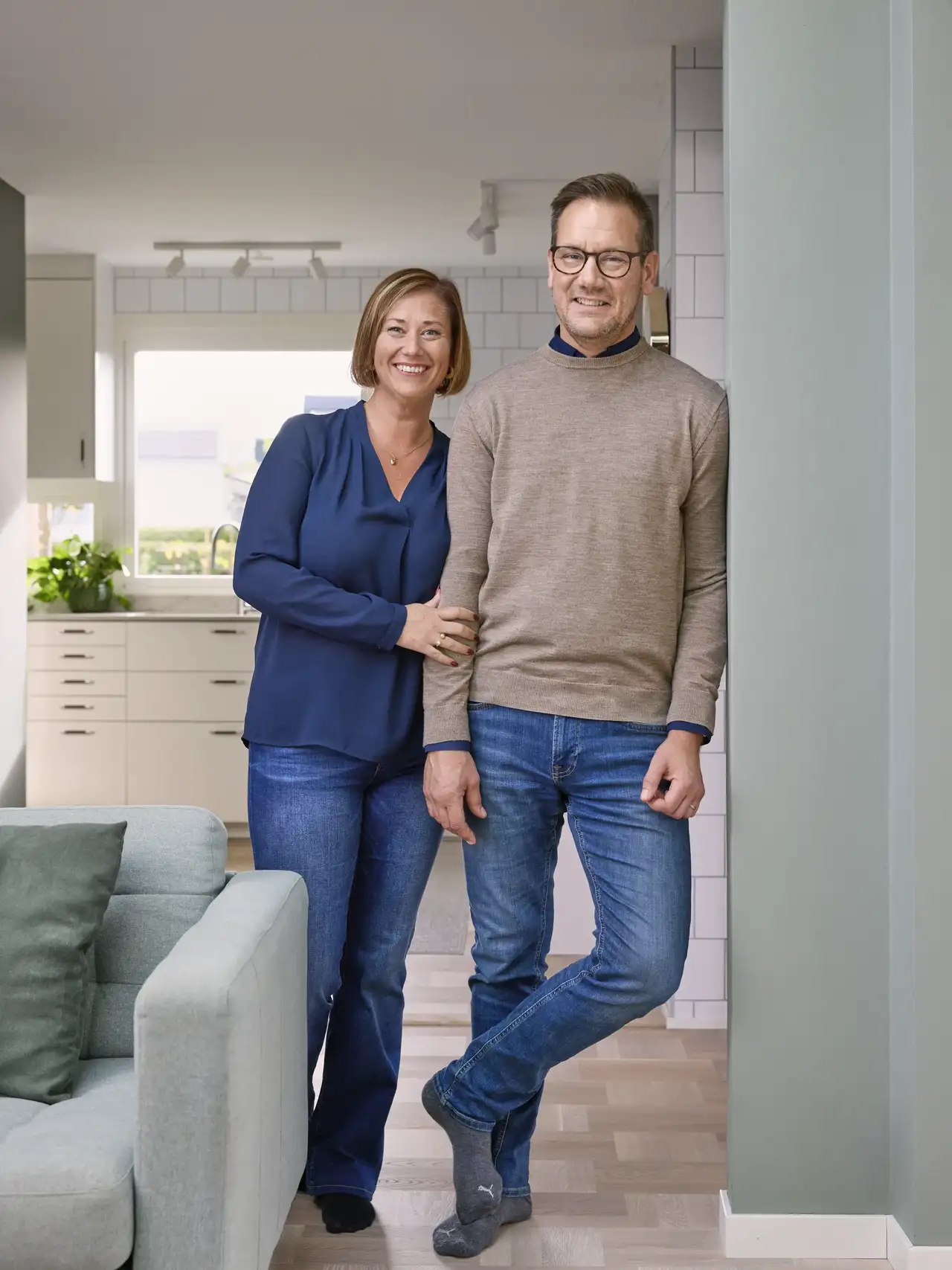 Et par står i et moderne hjem med stilrent kjøkken, en innbydende stue og takvindu.