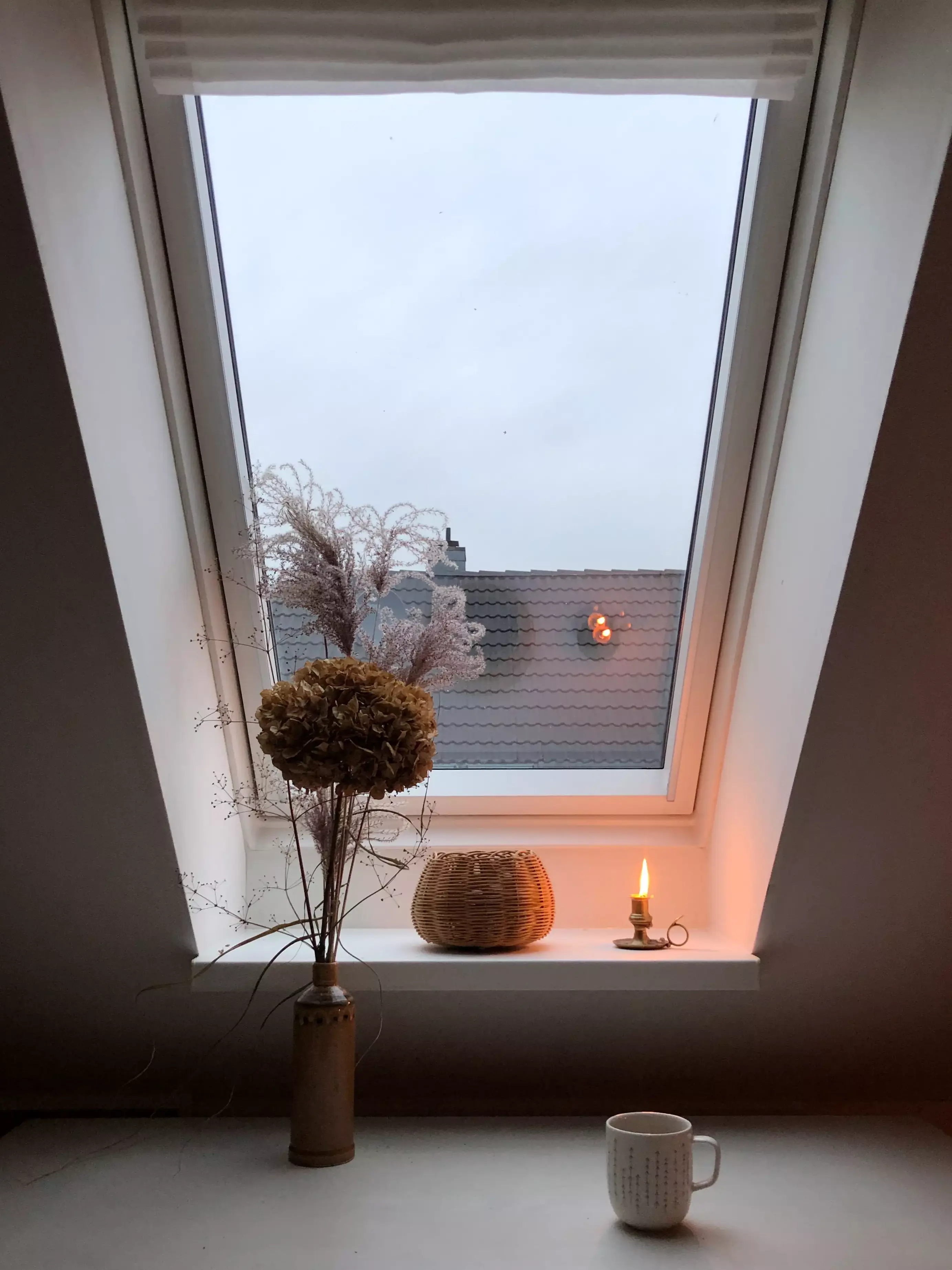 Fenêtre de toit VELUX éclairant un coin douillet avec des fleurs séchées, un panier et une bougie.
