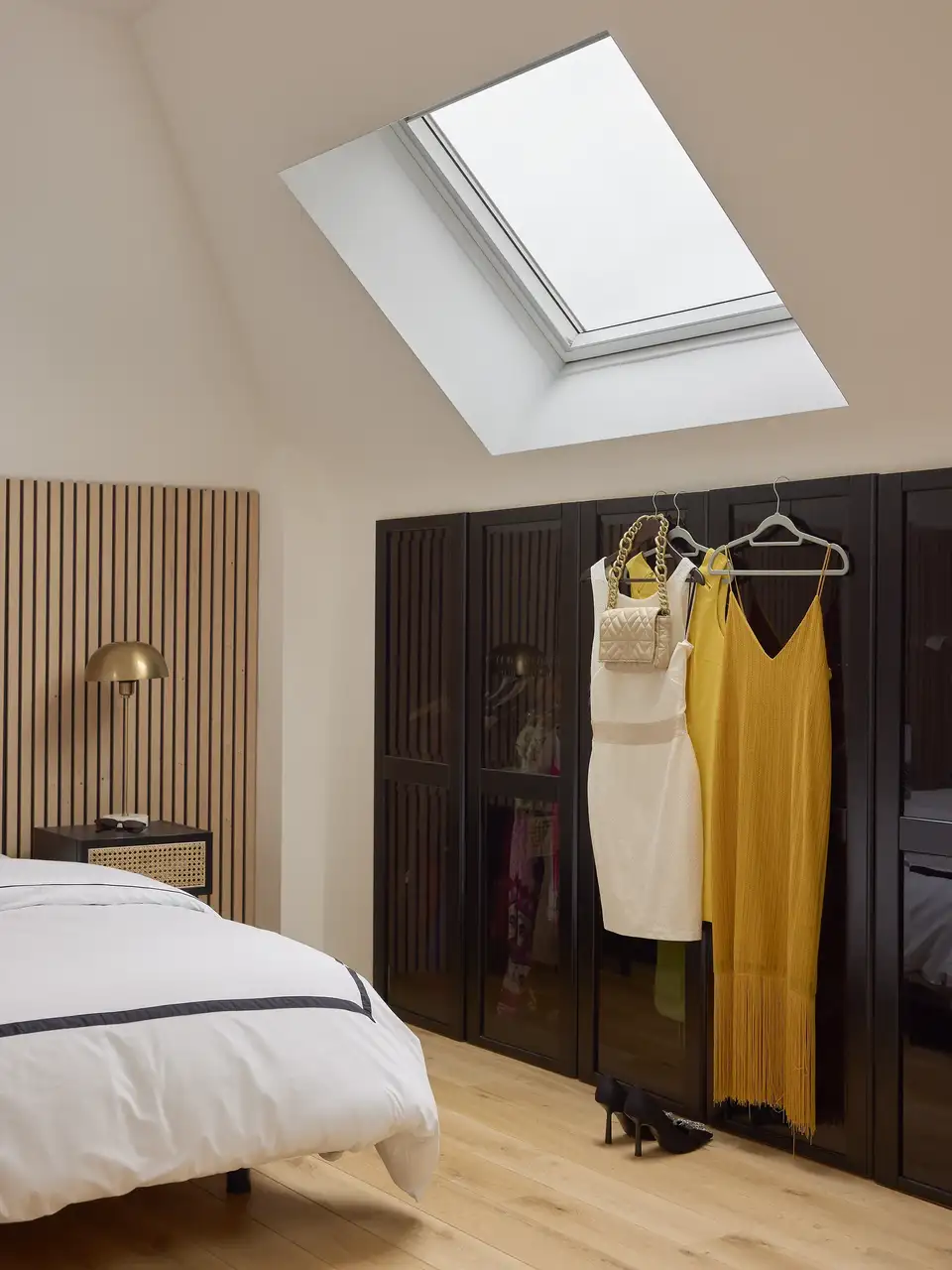 Vêtements de femme suspendus à l’extérieur de l’armoire dans une mansarde - VELUX