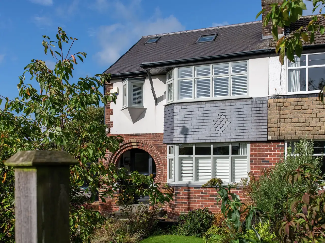 Terraced house with slate roof, VELUX windows, and brick facade.
