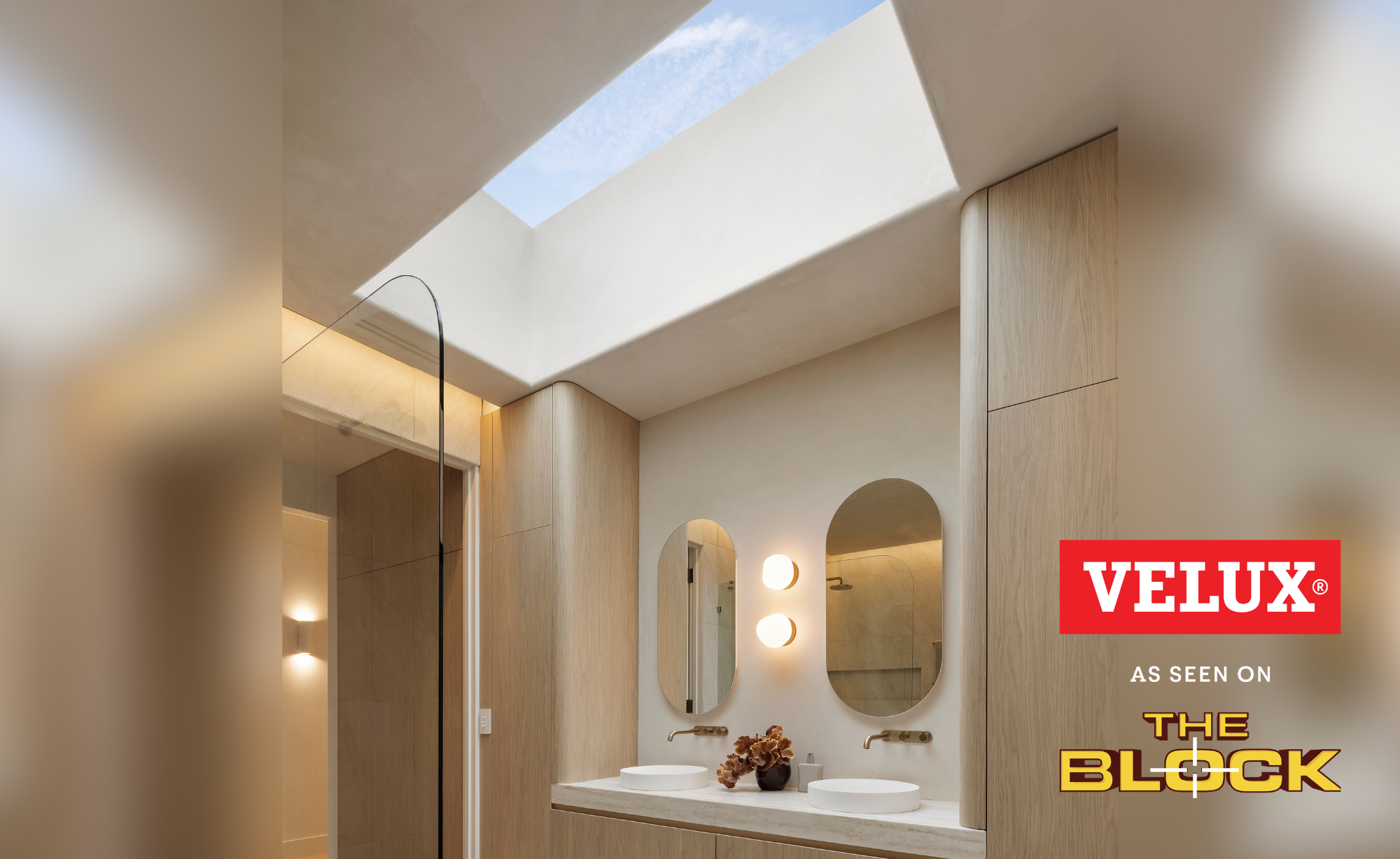 Modern bathroom with twin basins lit by a large VELUX flat roof window above.