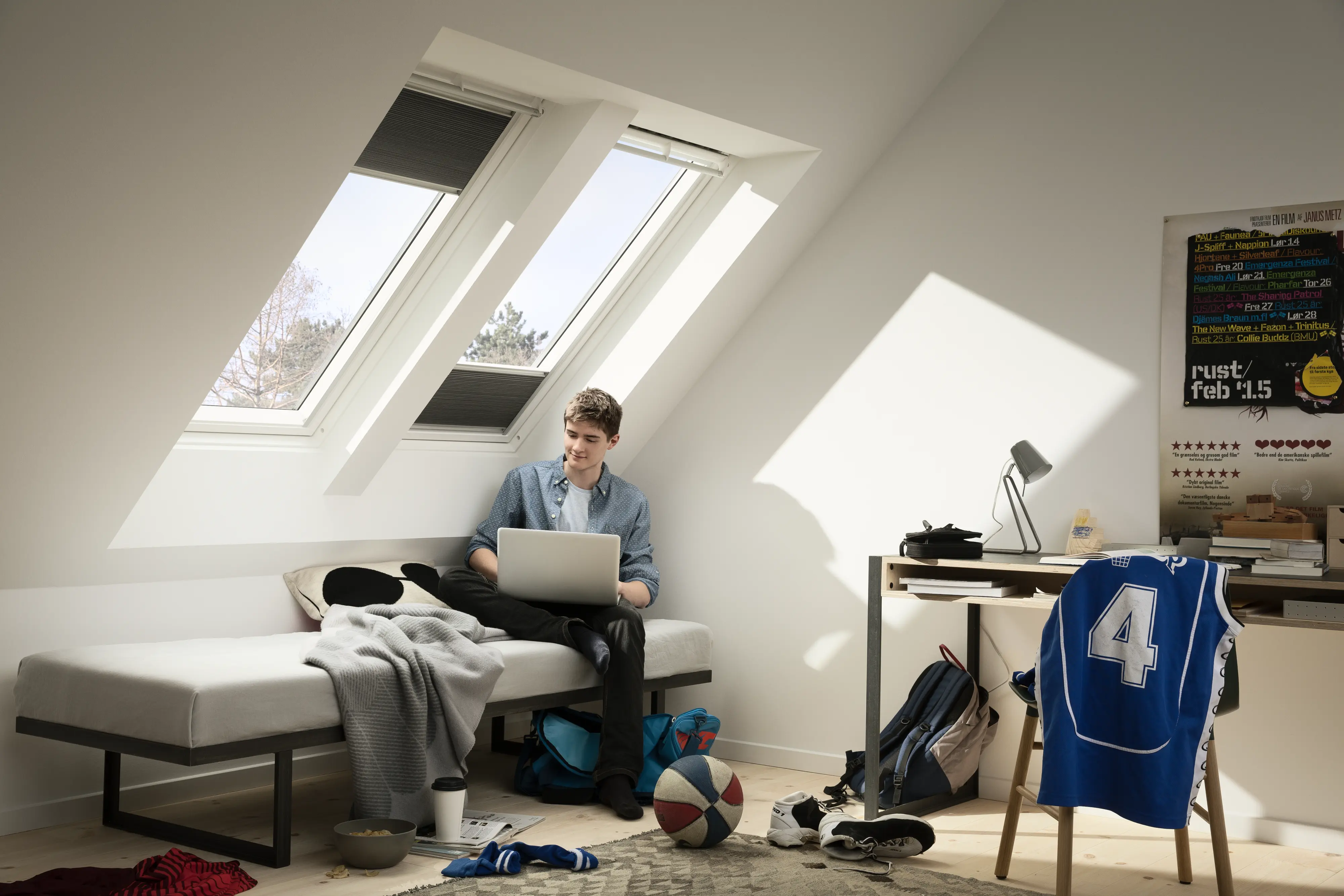 Mansarda s strešnimi okni VELUX, skozi katera vstopa nežna zimska svetloba.