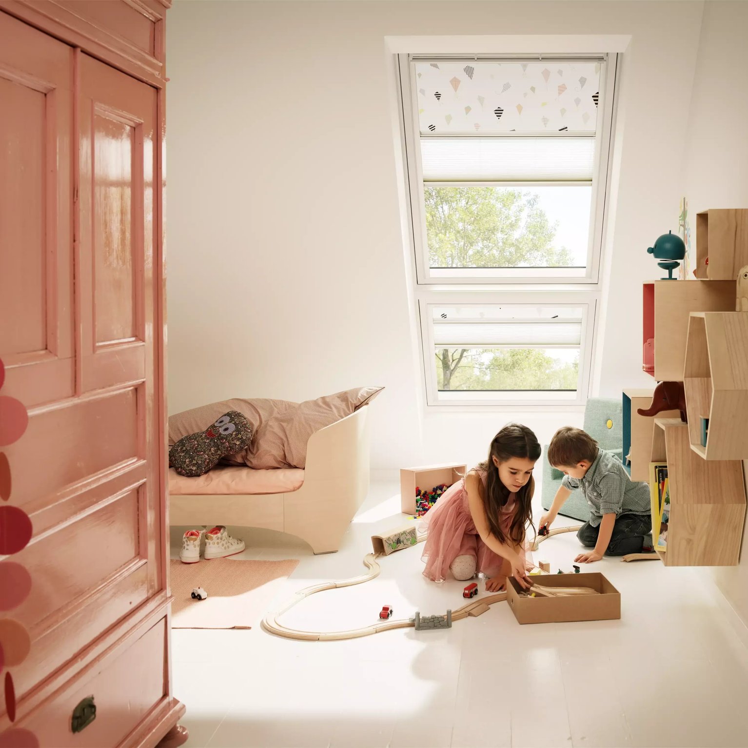 Kids room with sloped ceiling and VELUX roof window, children playing.