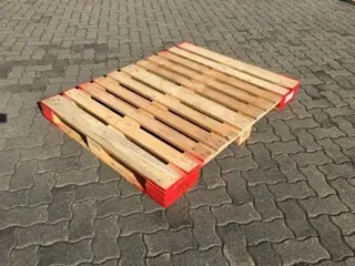 Single wooden pallet with red edges on sunlit concrete paving