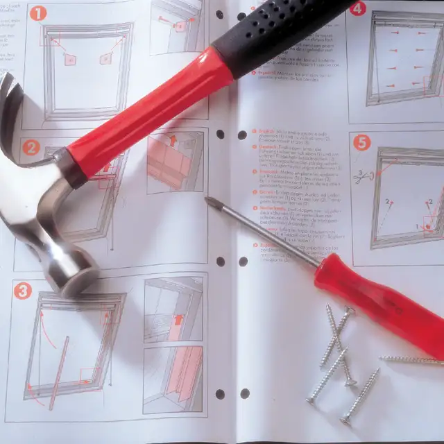 Hammer and screwdriver lying on installation guide for VELUX roof window blinds