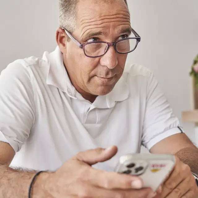 Mężczyzna trzymający smartfon w okularach, skupiony i zaangażowany w rozmowę. | VELUX