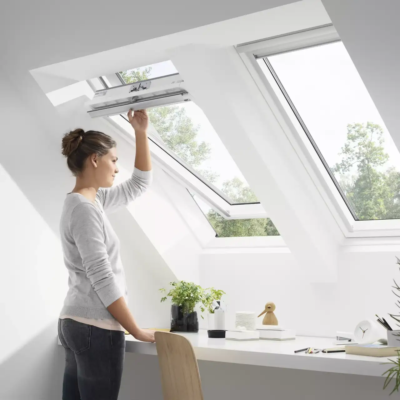 Modernes Dachboden-Homeoffice mit einem offenen VELUX Dachflächenfenster, Schreibtisch und Pflanzen.