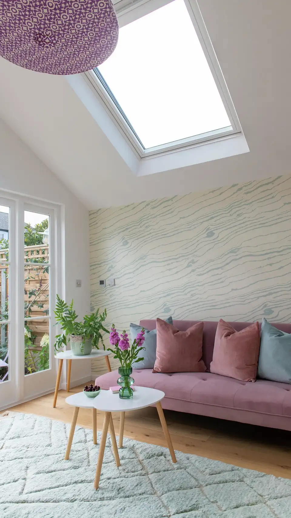 Salon avec accessoires rétro et coussins colorés, éclairé par la lumière naturelle d’une fenêtre de toit VELUX.