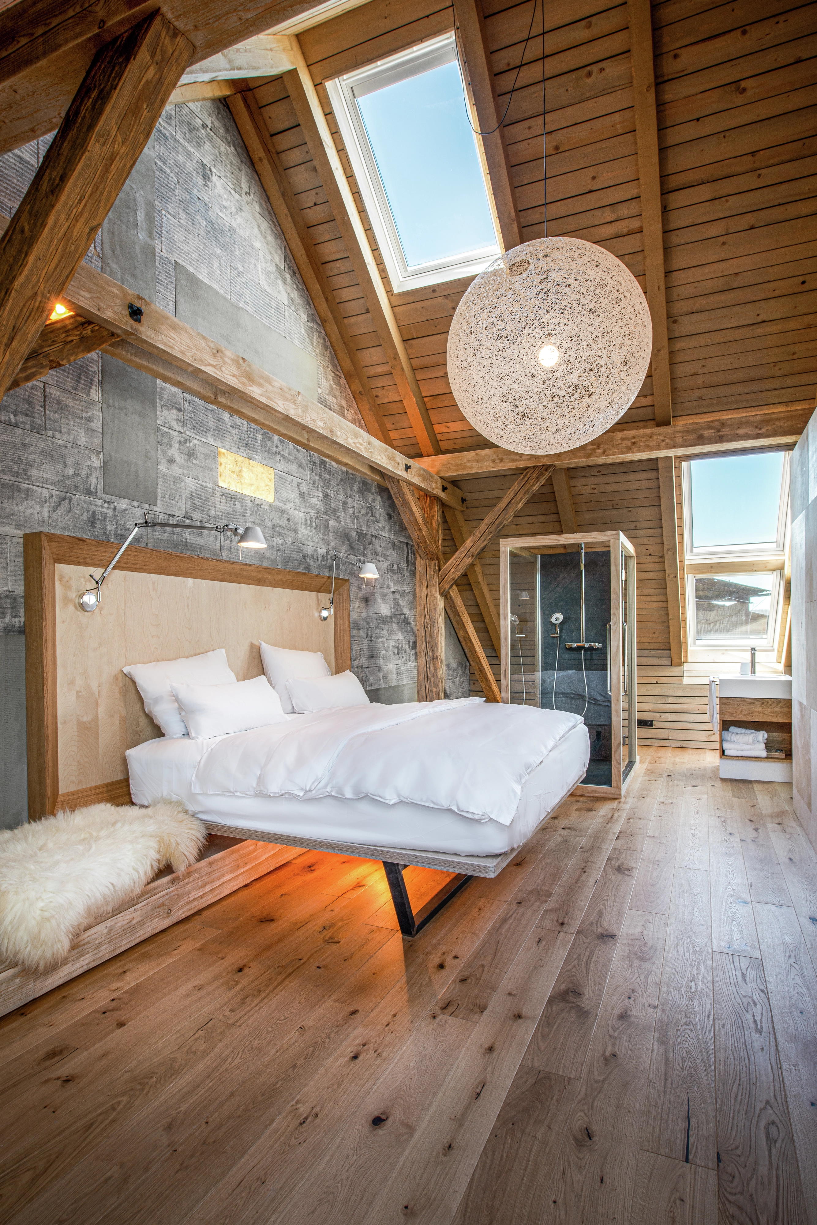 Attic bedroom with sloped ceiling, VELUX windows, and visible rafters.