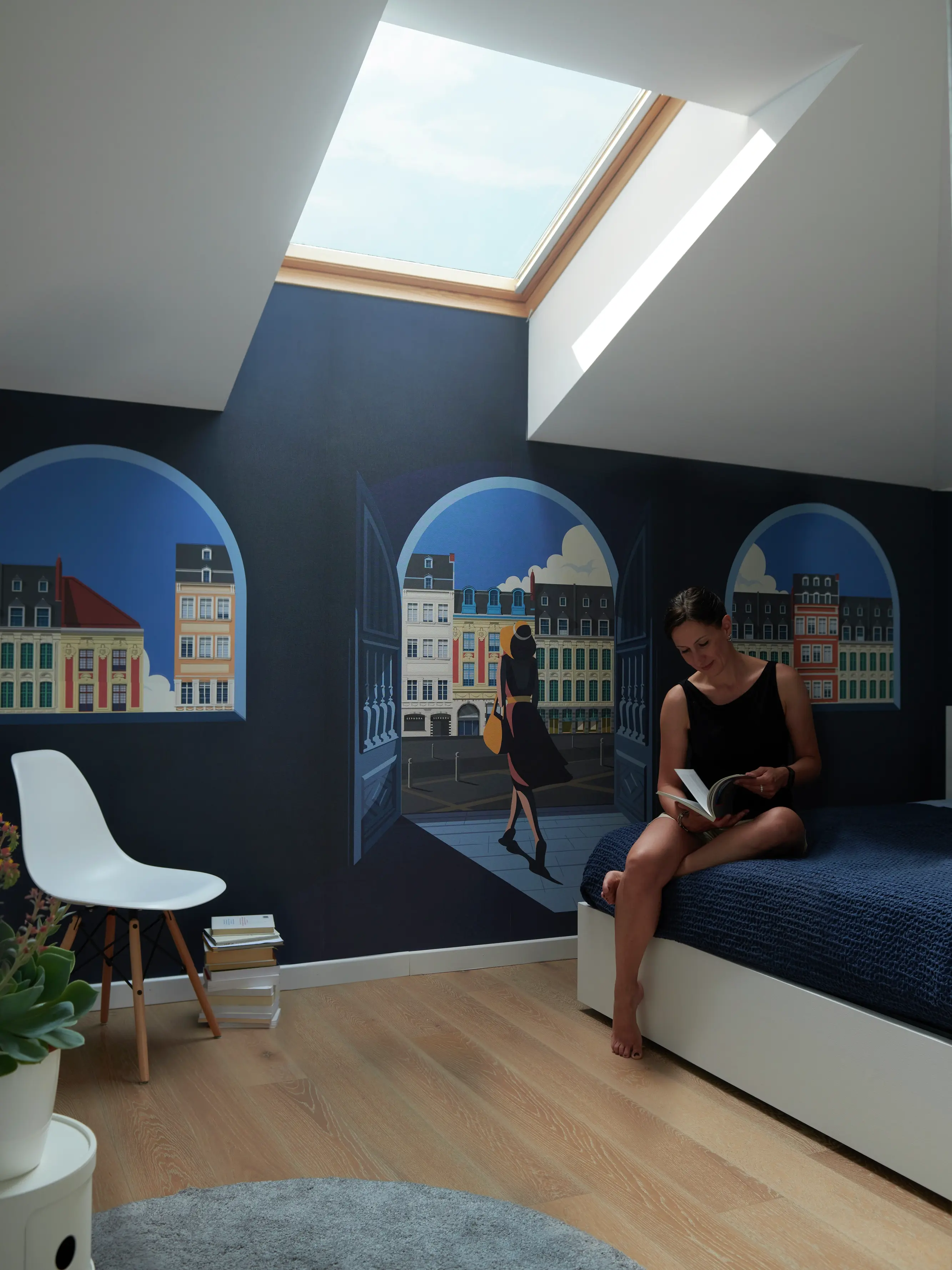 Chambre avec une peinture murale de paysage urbain et lumière naturelle provenant d'une fenêtre de toit VELUX.