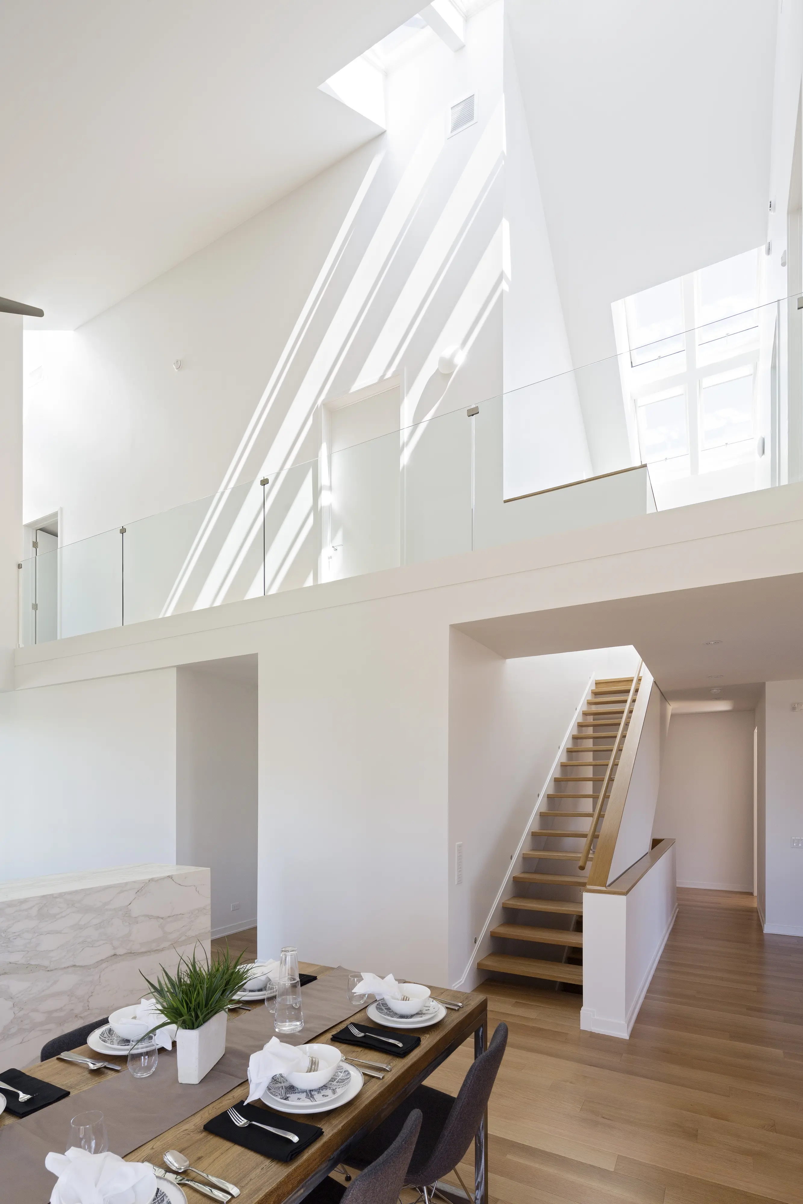 Sufragerie cu masă din lemn, fereastră de mansardă VELUX și scară.