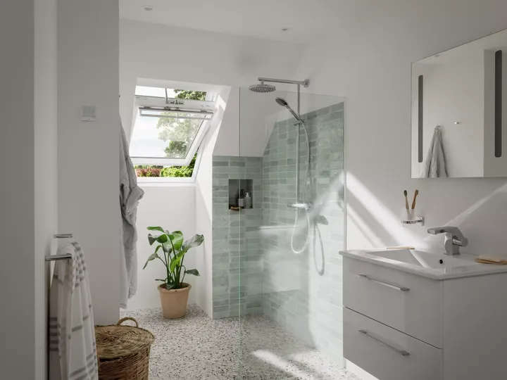 Modernes Badezimmer mit VELUX Dachflächenfenster, begehbarer Dusche und grünen Fliesen.