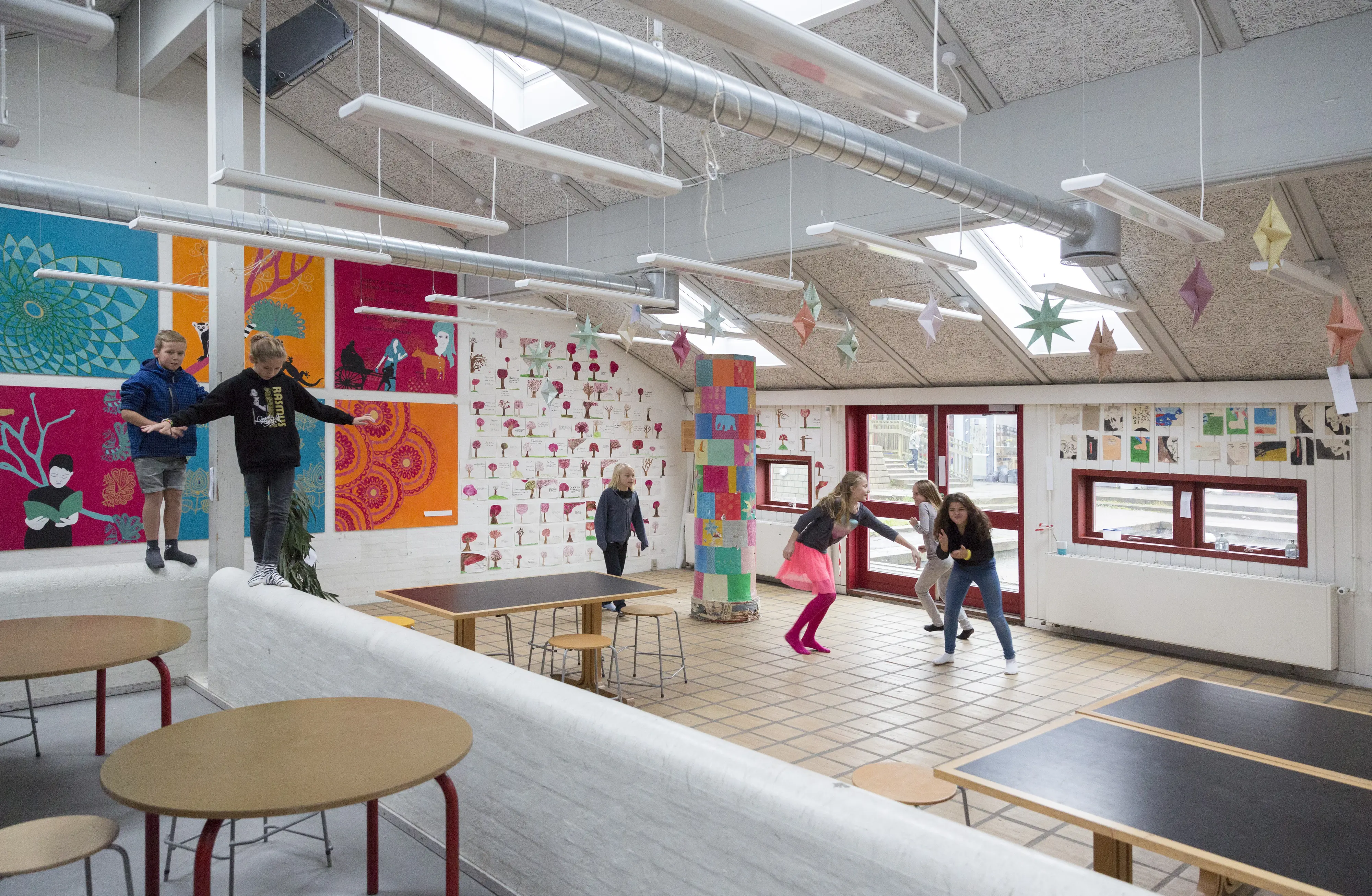 Sală de clasă cu decor colorat și ferestre de mansardă VELUX, copii jucându-se.
