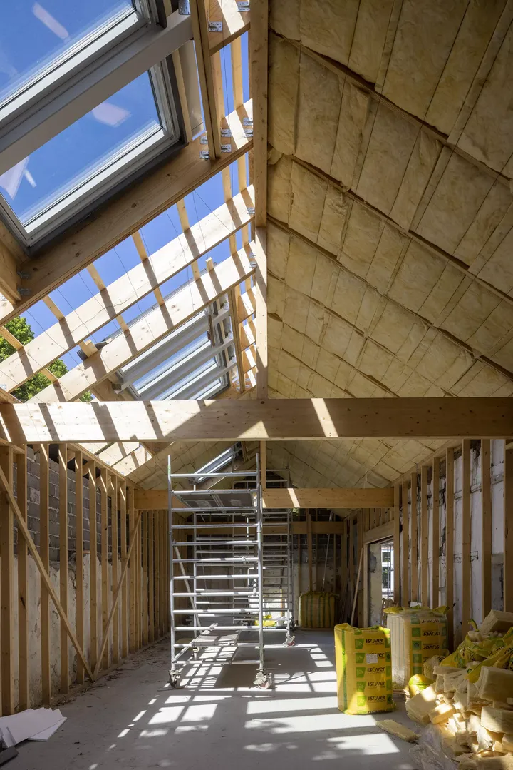 Innen eines Dachbodens unter Renovierung mit VELUX Dachflächenfenstern und Baumaterialien.