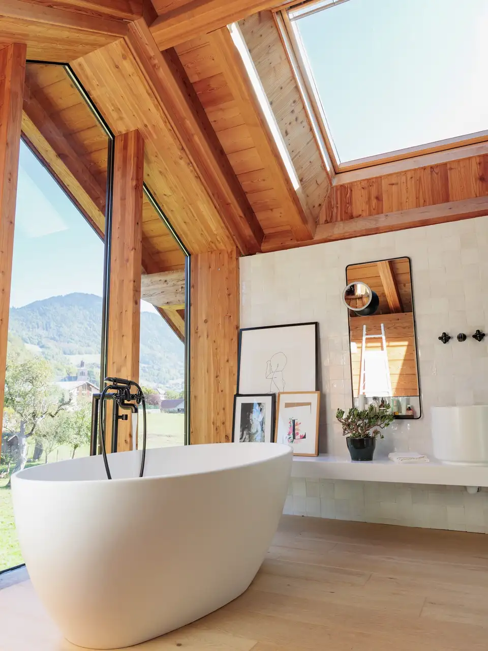 Cuarto de baño con bañera exenta, vistas al exterior, tejado y vigas de madera y ventana de tejado