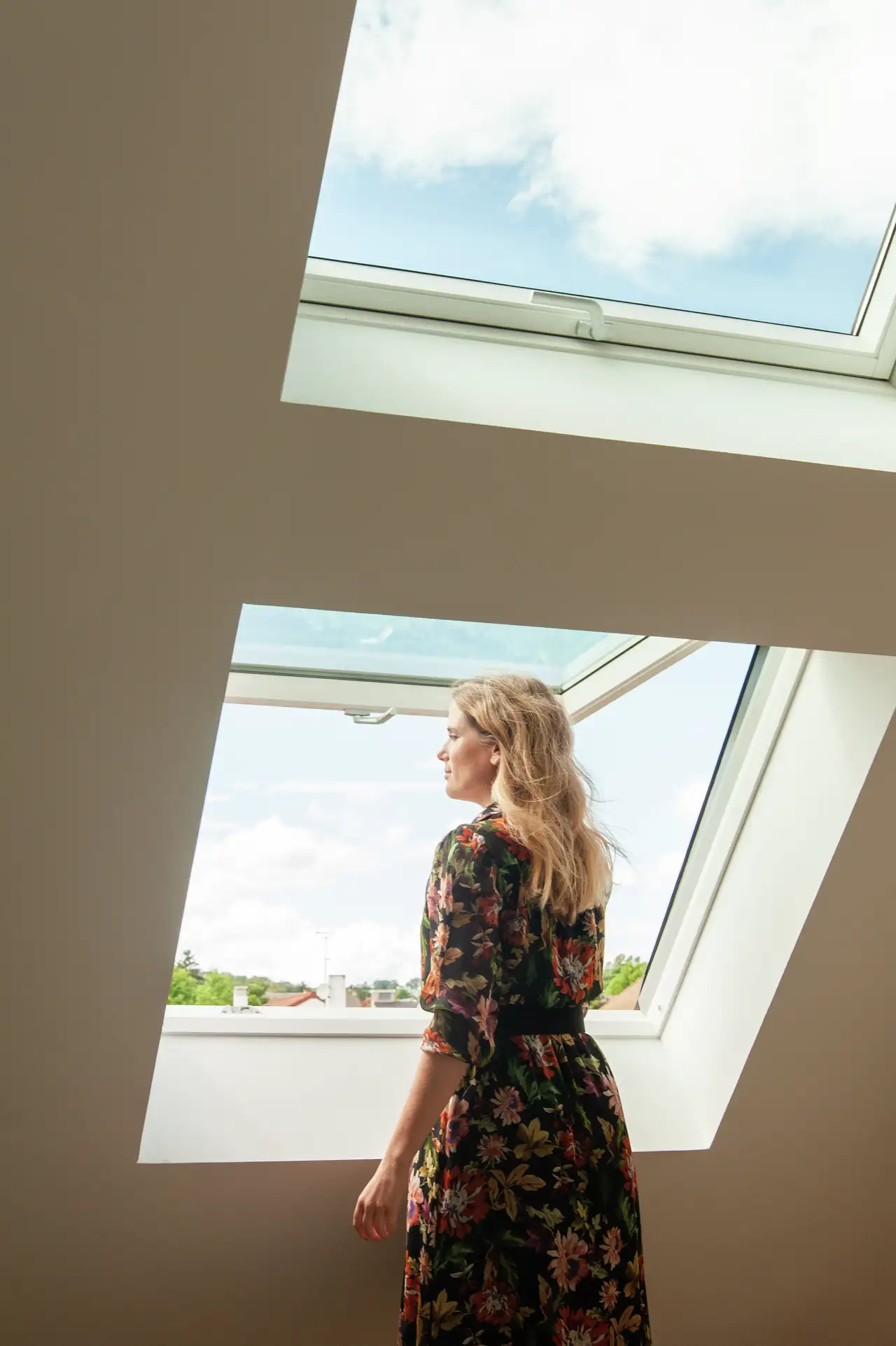 Een vrouw kijkt naar het landschap door een VELUX dakvenster.