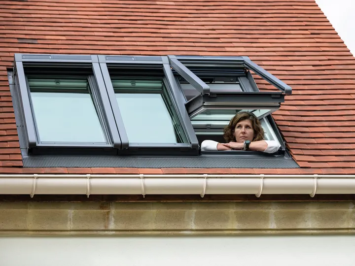 Öffnen Sie VELUX Dachflächenfenster, die in ein rotes Ziegeldach integriert sind, gegen einen klaren Himmel.