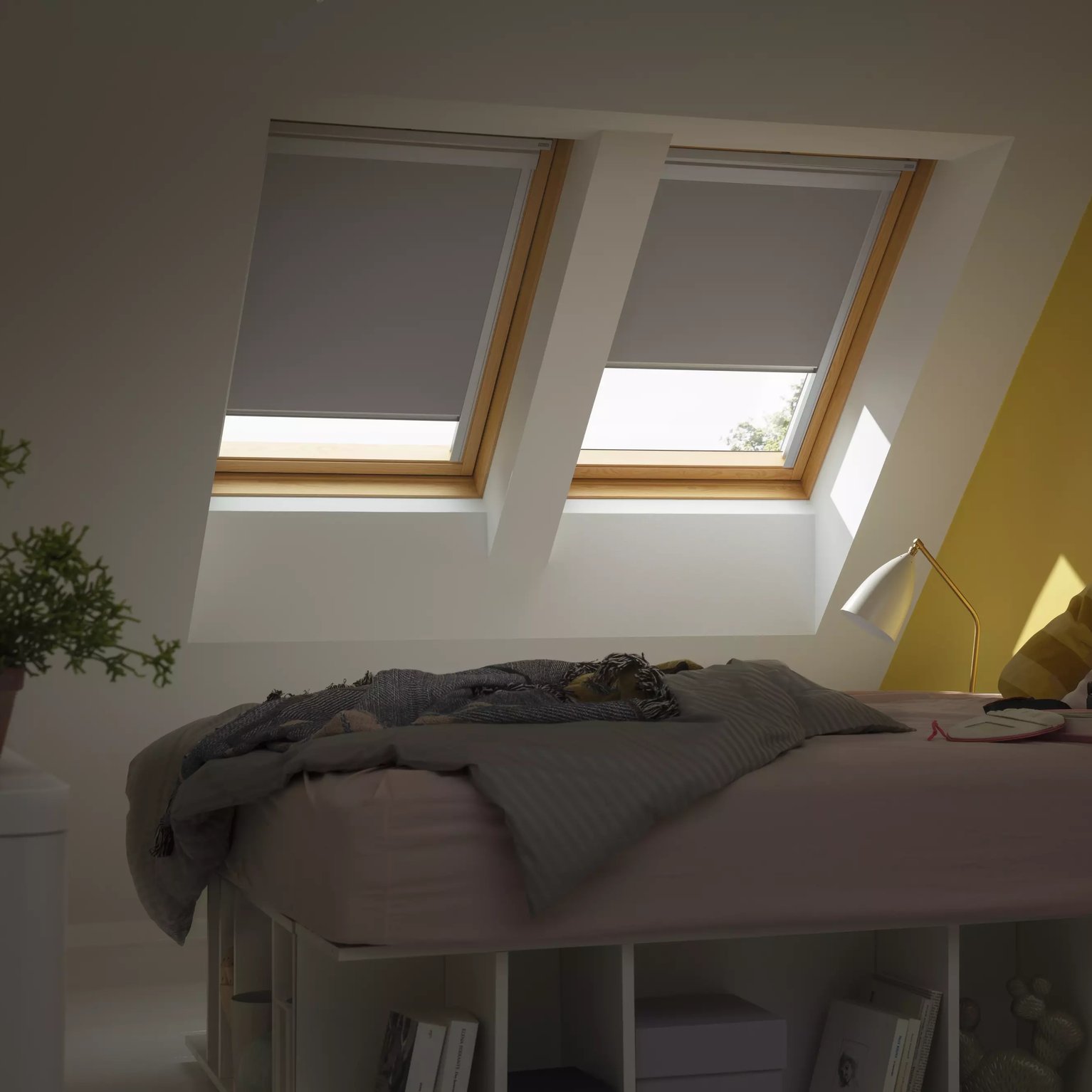 Attic bedroom with sloped ceiling and VELUX roof windows, cozy decor.