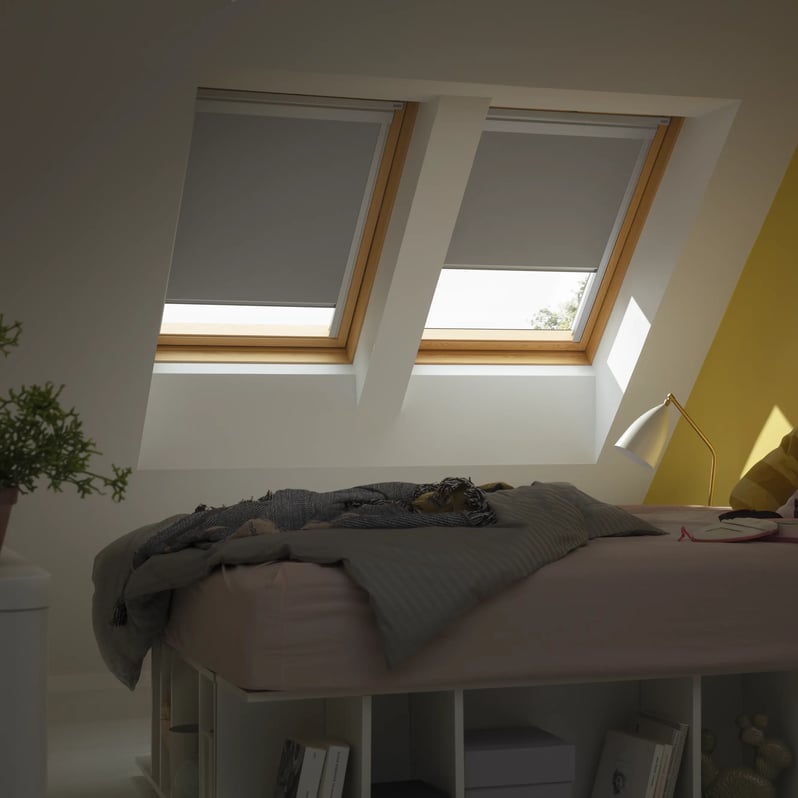 Attic bedroom with sloped ceiling and VELUX roof windows, cozy decor.