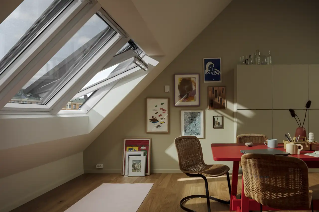 Stanza in mansarda con tre finestre per tetti affiancate con tende e sistema smart VELUX ACTIVE