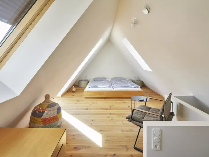 Schlafzimmer im Dachboden mit VELUX Dachflächenfenster und hölzernen Böden.