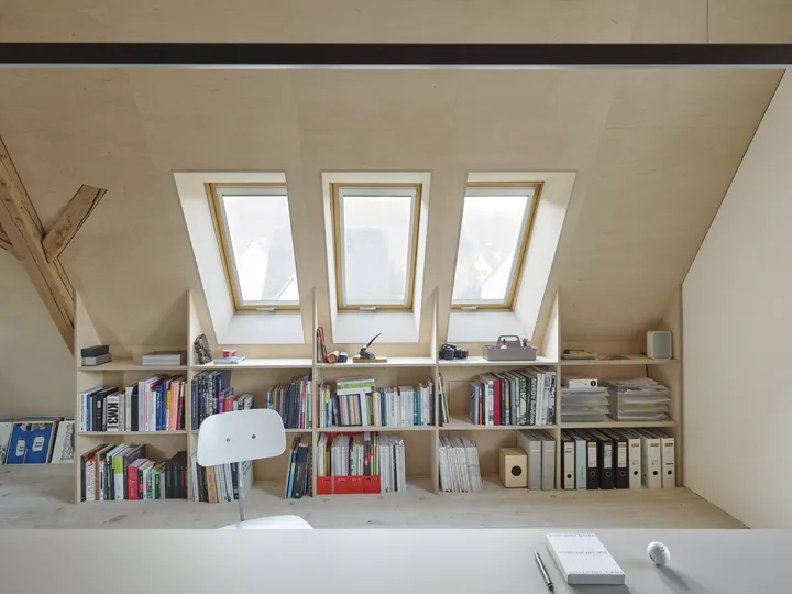 Dachboden-Heimbüro mit natürlichem Licht von VELUX Dachflächenfenstern und eingebauten Bücherregalen.