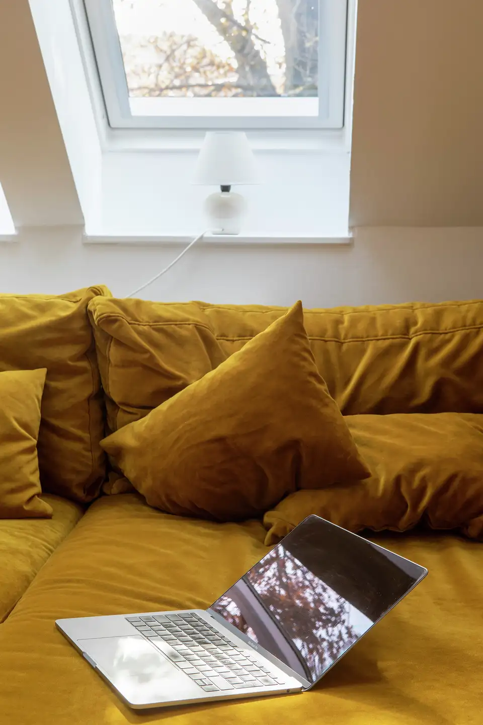 Détail d’un canapé en velours éclairé par la lumière naturelle d’une fenêtre de toit VELUX.