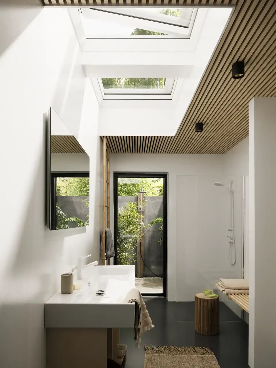 Salle de bain étroite en mansarde avec une fenêtre verticale et deux grandes fenêtres de toit plat.