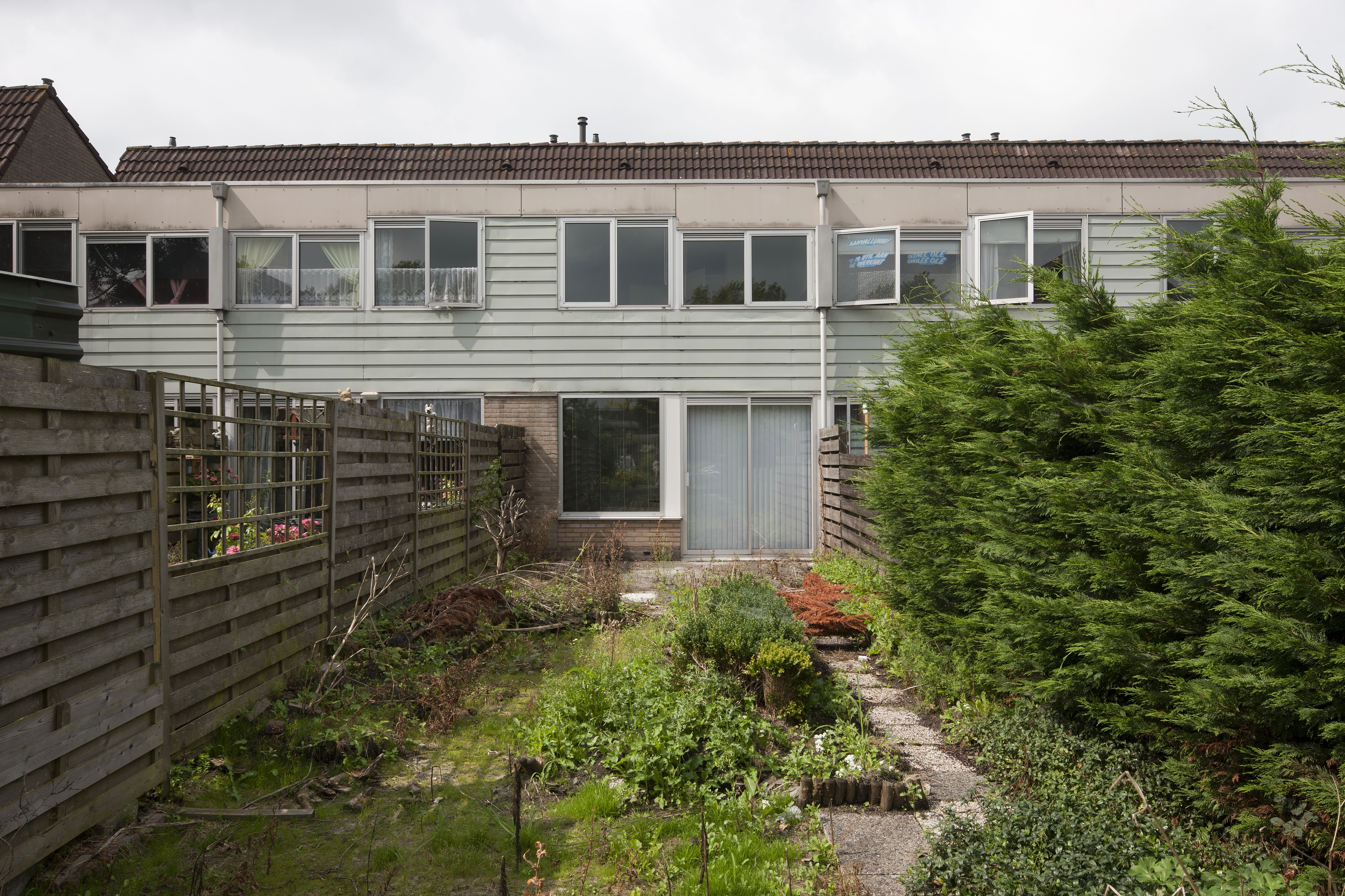 Terraced house with tiled roof and garden, windows open for fresh air.
