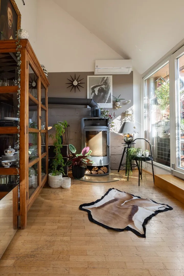 Dachboden-Wohnzimmer mit VELUX-Fenster, Holzofen, Pflanzen und Vintage-Dekor.