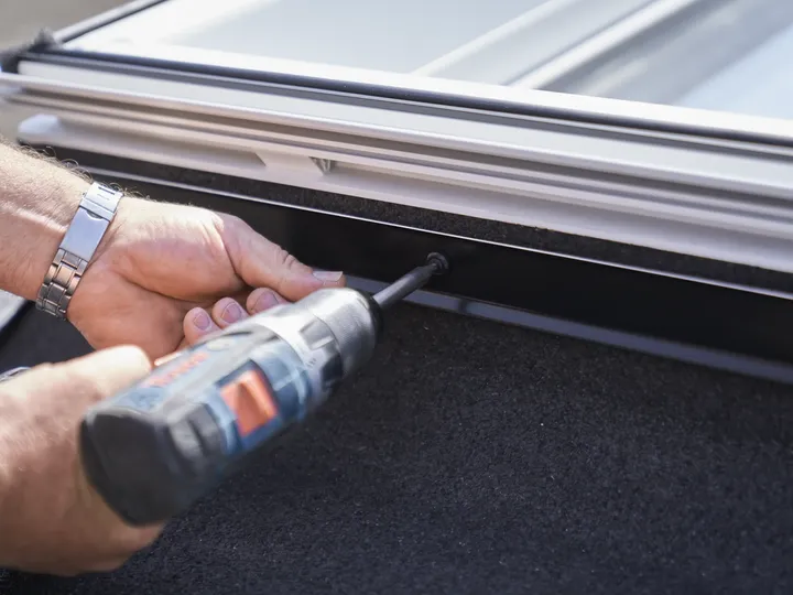 Dachdecker schraubt mit einem Akkuschrauber am Dachfensterrahmen | VELUX Magazin