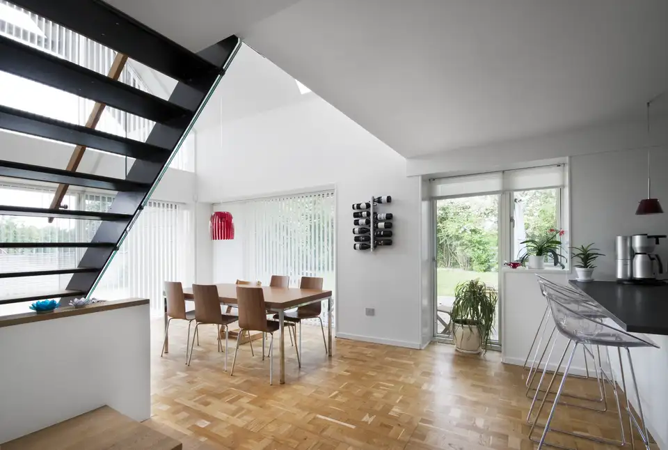 Intérieur de style Bauhaus avec escalier métallique, mobilier en bois et larges fenêtres laissant entrer la lumière naturelle