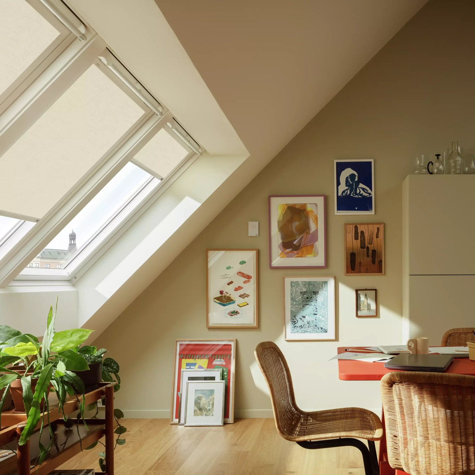 Attic workspace with sloped ceiling, VELUX roof windows, and vibrant decor.