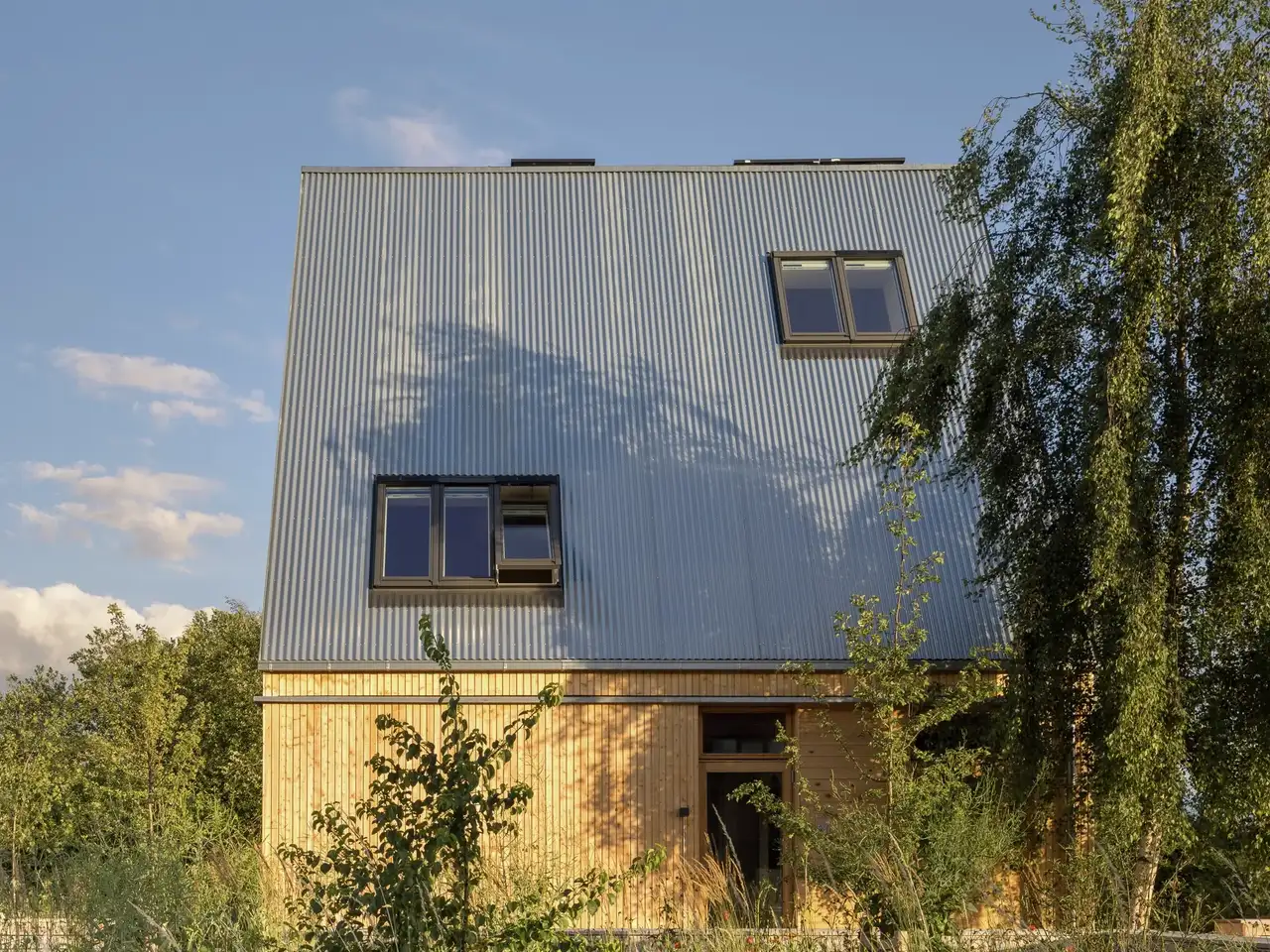 Modernes Zuhause mit Metallverkleidung und VELUX Dachflächenfenster, umgeben von Grünanlagen.