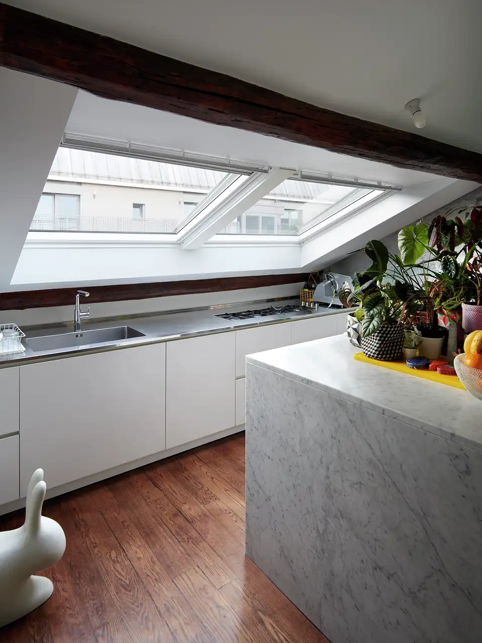 Cucina moderna in mansarda con piano di lavoro sotto una grande finestra per tetti 