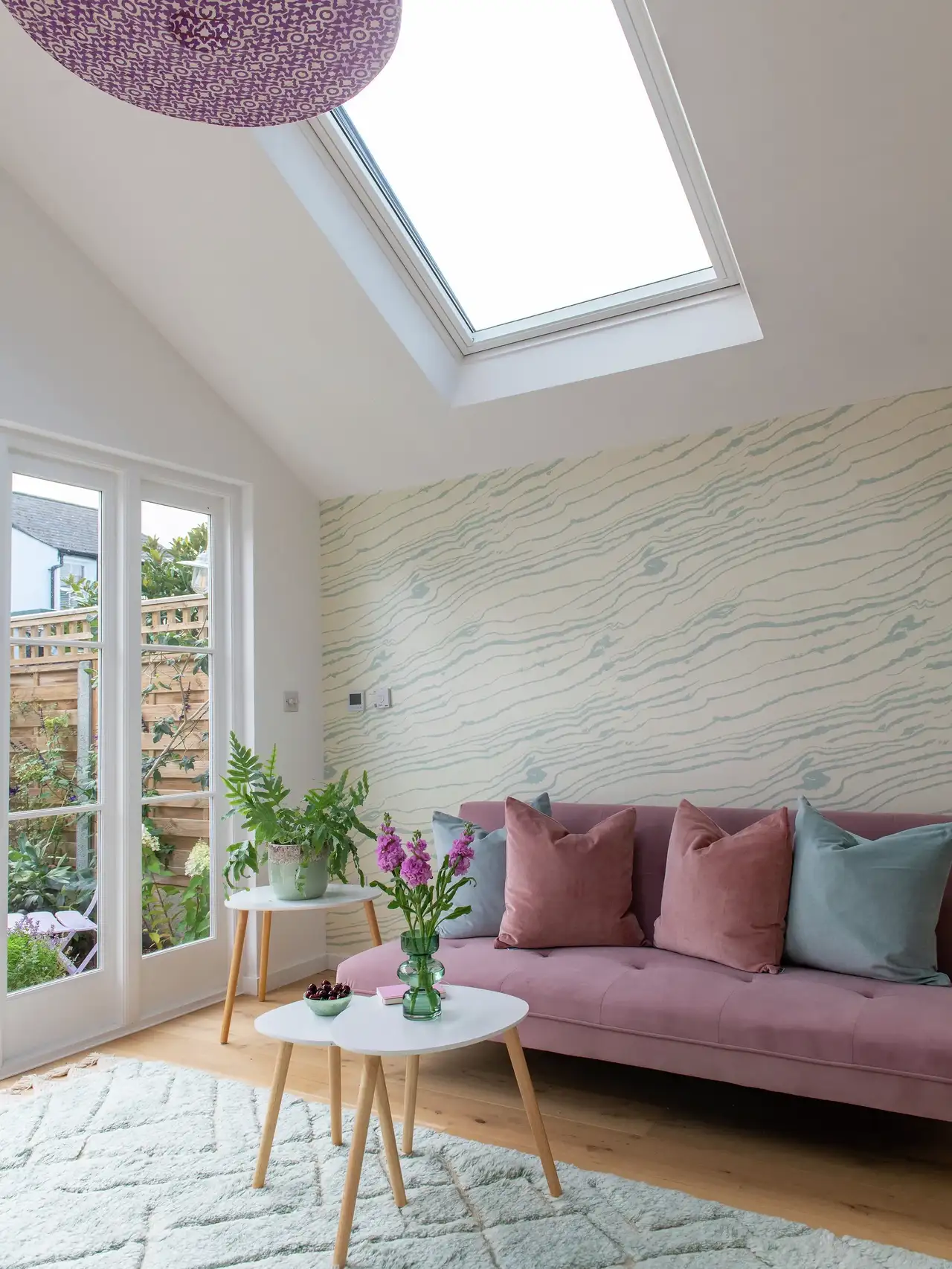 Salon sous combles avec mur tapissé derrière le canapé