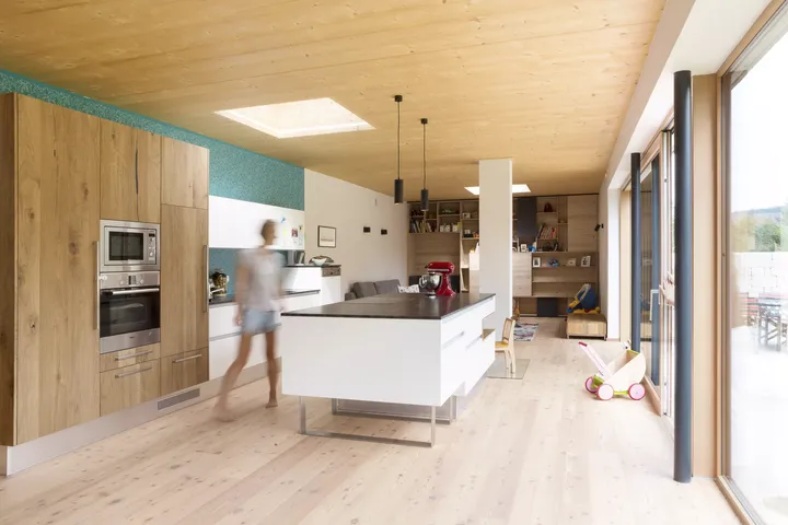 Helle moderne Küche mit weißer Insel, hölzernen Schränken und einem VELUX Dachflächenfenster.